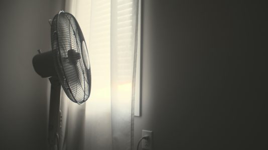 ventilateur au sol devant la fenêtre avec les rideaux fermés